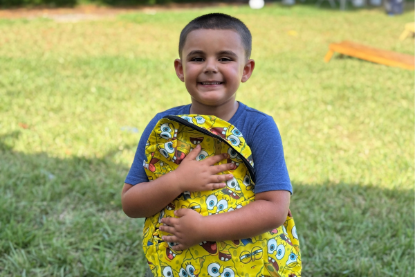 child hugging a backpack